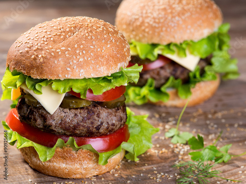 Big hamburger with beef cutlet and vegetables on wood plate