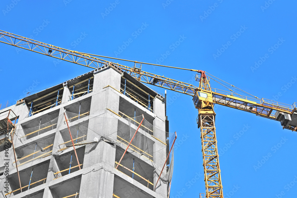 Crane and building construction site against blue sky Crane and building construction site against blue sky