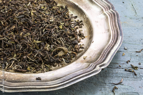Bilde på lerret loose black Darjeeling Tea on a silver plate on rustic blue pain