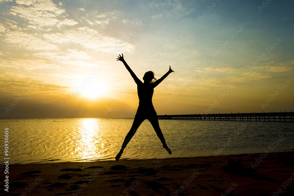 Happy young woman jumping against beautiful sunrise