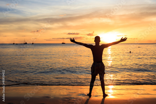 African  men raising arms up  at Sunset in Tarrafal beach in San