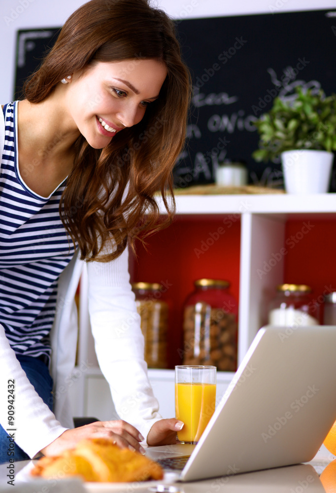 Attractive young woman using laptop and sitting in the kitchen Attractive young woman using laptop and sitting in the kitchen