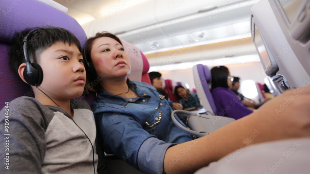 happy asian family playing and watching monitor on air plane happy asian family playing and watching monitor on air plane
