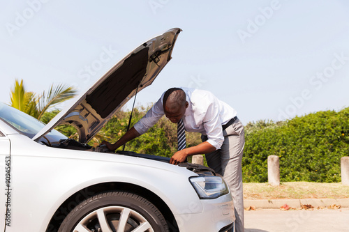 Fotografi afro american man looking at broken down car engine