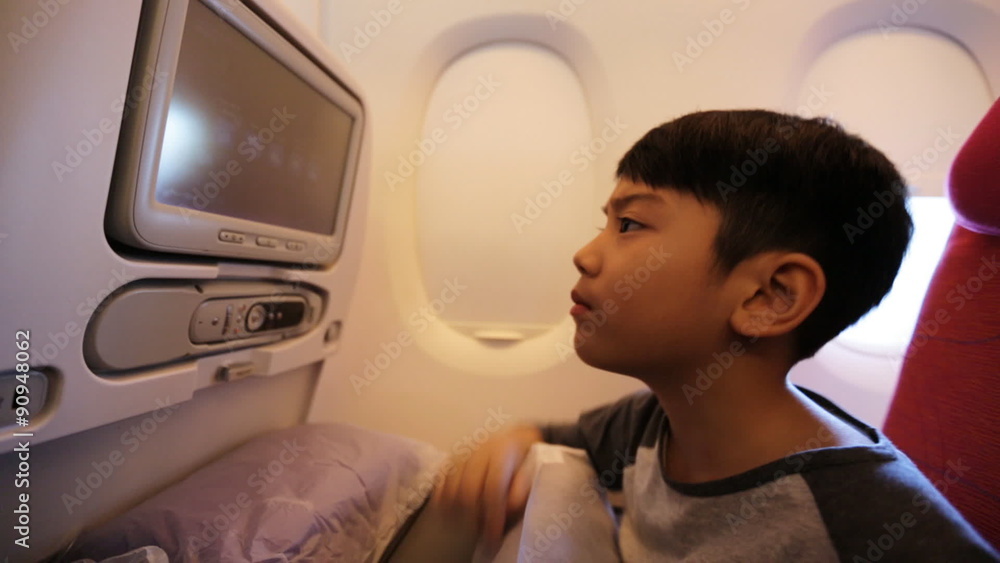 Young asian kid relaxing watching movie inside airplane. Young asian kid relaxing watching movie inside airplane.