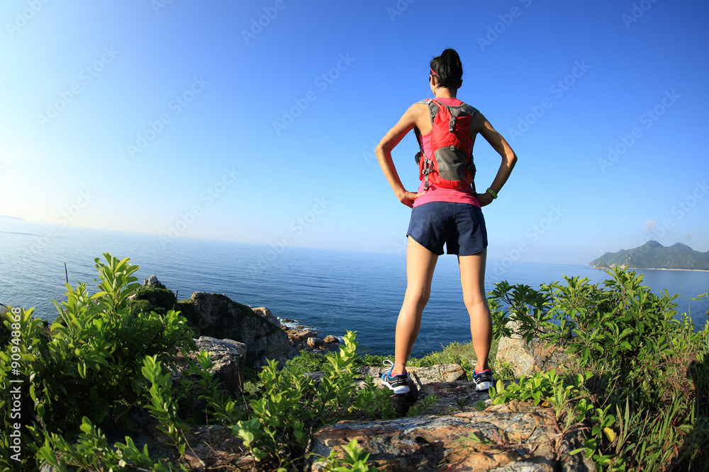  young fitness woman trail runner/ hiker on seaside mountain peak