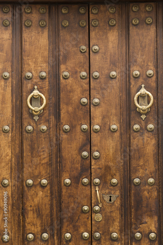 Puerta rústica de madera con adornos dorados. © Lola Fdez. Nogales