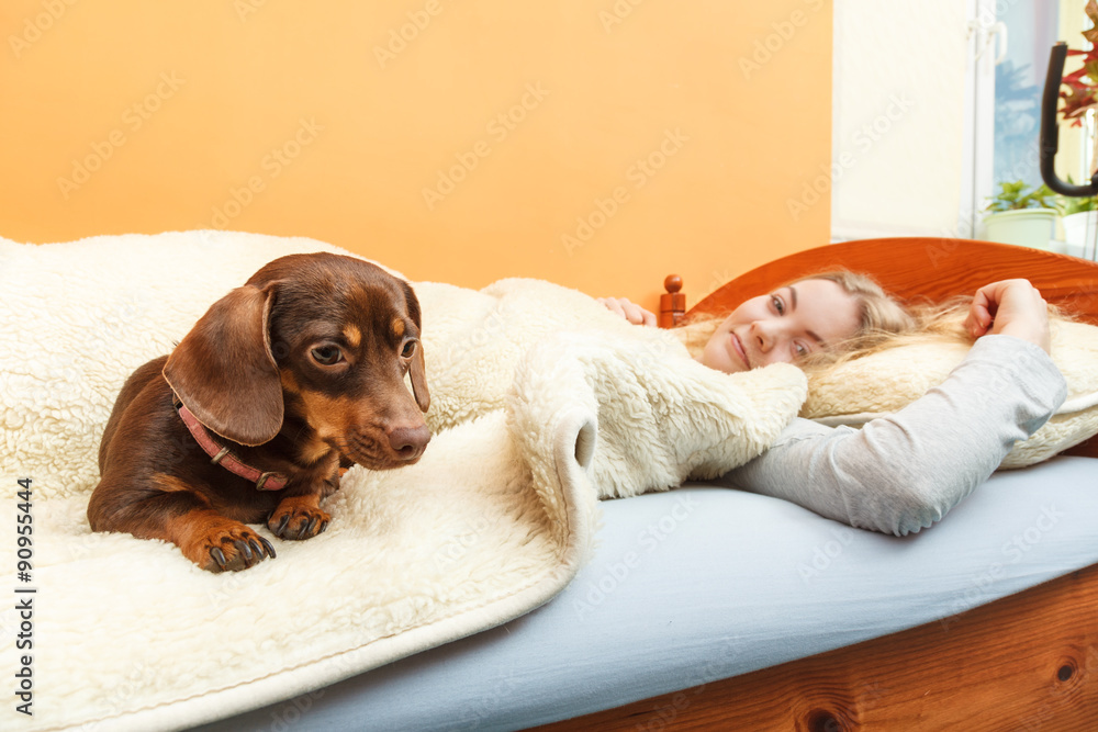 Woman with dog waking up in bed after sleeping.