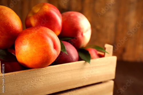Fresh peaches in crate on wooden background