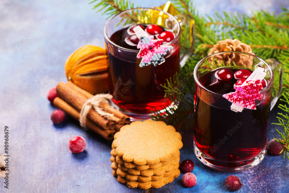 Hot xmas punch with spices and cranberry in glass cups and ginger cookies. Christmas or new year background with decorations. Selective focus Hot xmas punch with spices and cranberry in glass cups and ginger cookies. Christmas or new year background with decorations. Selective focus