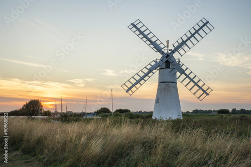 Stunning landscape of windmill and river at dawn on Summer morni