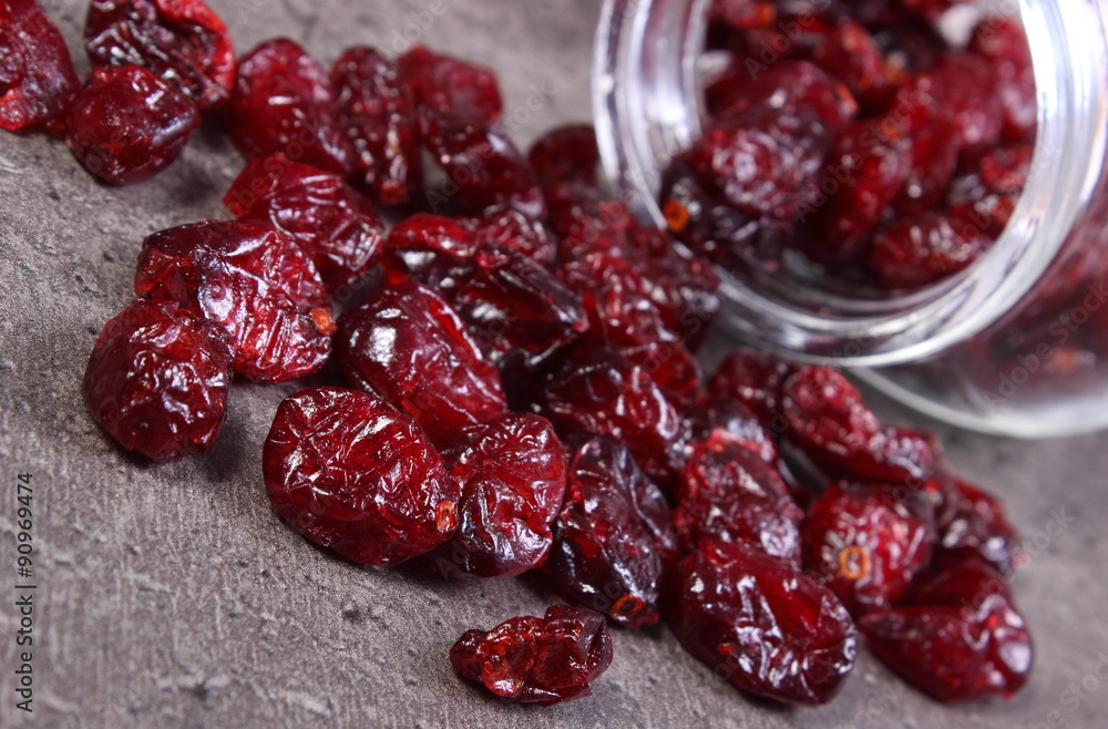Cranberries spilling out of glass jar on concrete Cranberries spilling out of glass jar on concrete