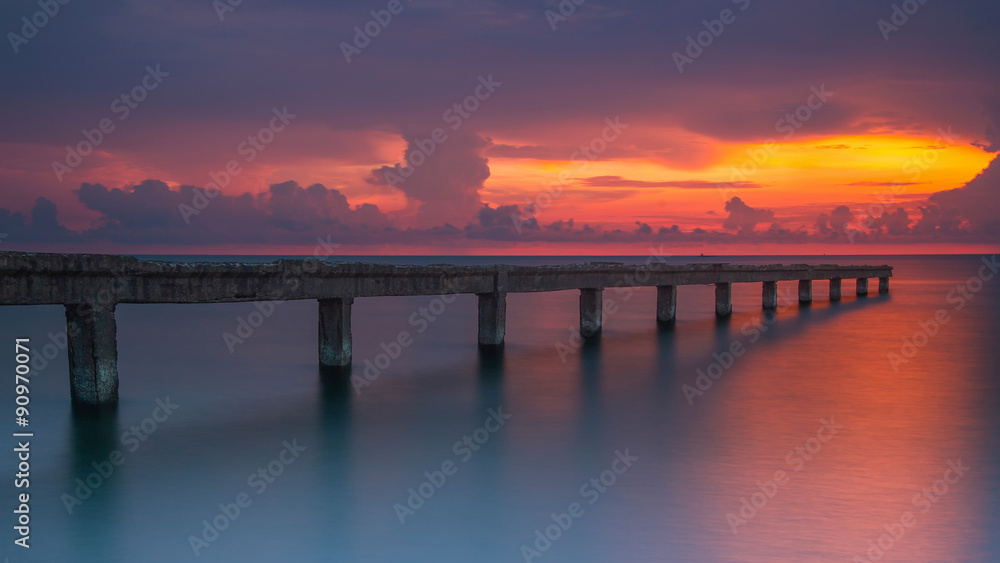 Beautiful sunrise at the sea with stone bridge