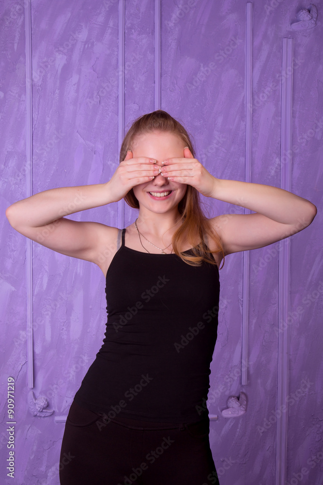 Fototapeta premium Portrait of young woman in a black closed her eyes with her hand