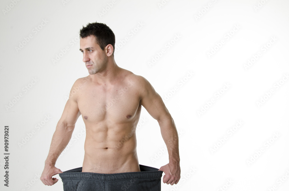 Fototapeta premium Muscular fit man wearing big pants after diet. Men's health problems. Headache and stress.