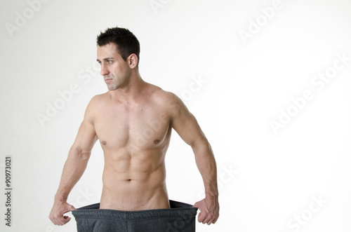 Muscular fit man wearing big pants after diet. Men's health problems. Headache and stress.