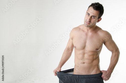 Muscular fit man wearing big pants after diet