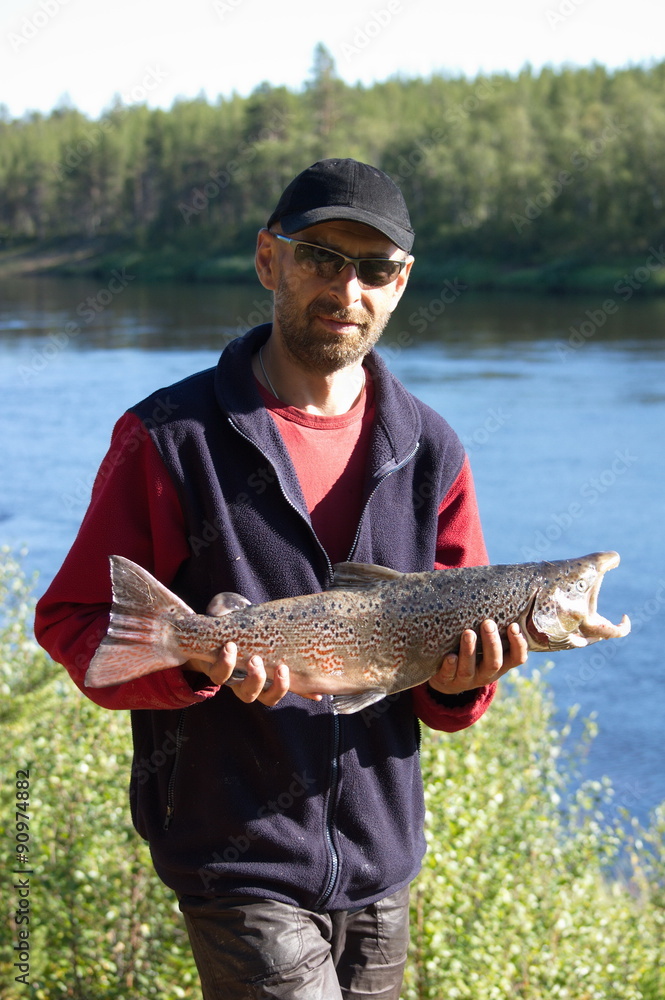 Fisherman caught a nice male salmon. Ponoy river, Kola Peninsula, Russia. Fisherman caught a nice male salmon. Ponoy river, Kola Peninsula, Russia.