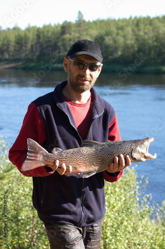 Fisherman caught a nice male salmon. Ponoy river, Kola Peninsula, Russia.