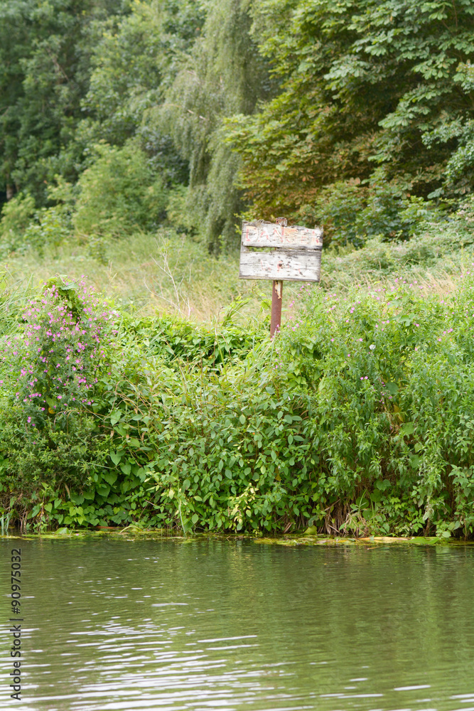 Faded wood Danger Deep Water sign on river bank Faded wood Danger Deep Water sign on river bank