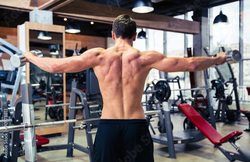 Back view portrait of man workout with dumbbells