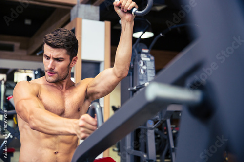 Bodybuilder doing exercise on fitness machine in gym