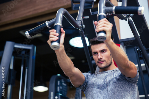 Bodybuilder doing exercise on fitness machine in gym