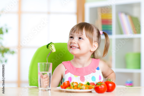 Kid eating healthy vegetables meal in home or nursery