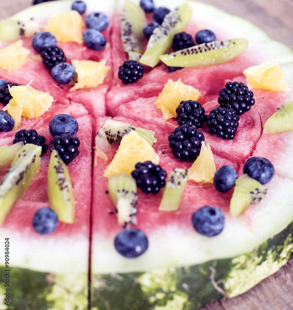 colorful tropical fruit watermelon pizza topped with kiwifruit, blueberries, orange and fresh berries cut into segments on a rustic wooden board colorful tropical fruit watermelon pizza topped with kiwifruit, blueberries, orange and fresh berries cut into segments on a rustic wooden board
