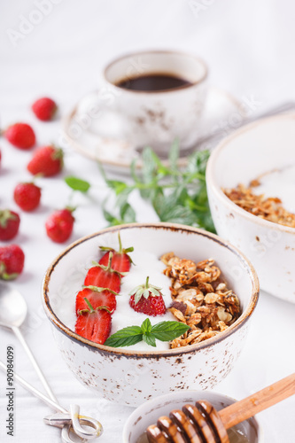 The homemade granola with fresh strawberries ,honey, mint and a Cup of coffee. Healthy Breakfast.selective focus