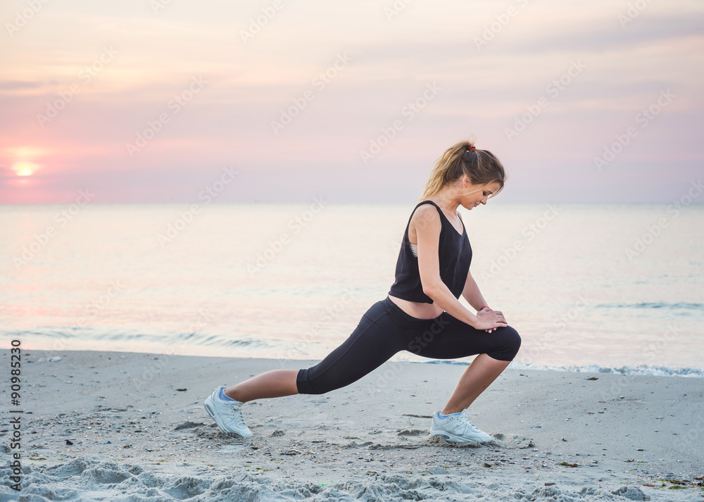 Fitness sport model smiling happy doing exercises during outdoor work out on sunrise. Beautiful caucasian female training outside on seaside in the morning Fitness sport model smiling happy doing exercises during outdoor work out on sunrise. Beautiful caucasian female training outside on seaside in the morning
