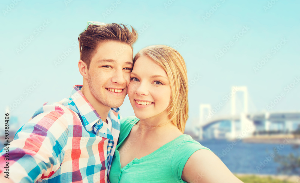 smiling couple taking selfie over bridge smiling couple taking selfie over bridge