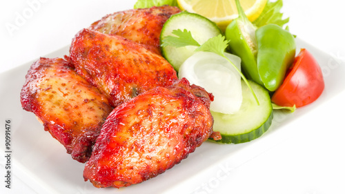 Tikka Hot Wings - Spicy and hot chicken wings served with salad on a white background.

