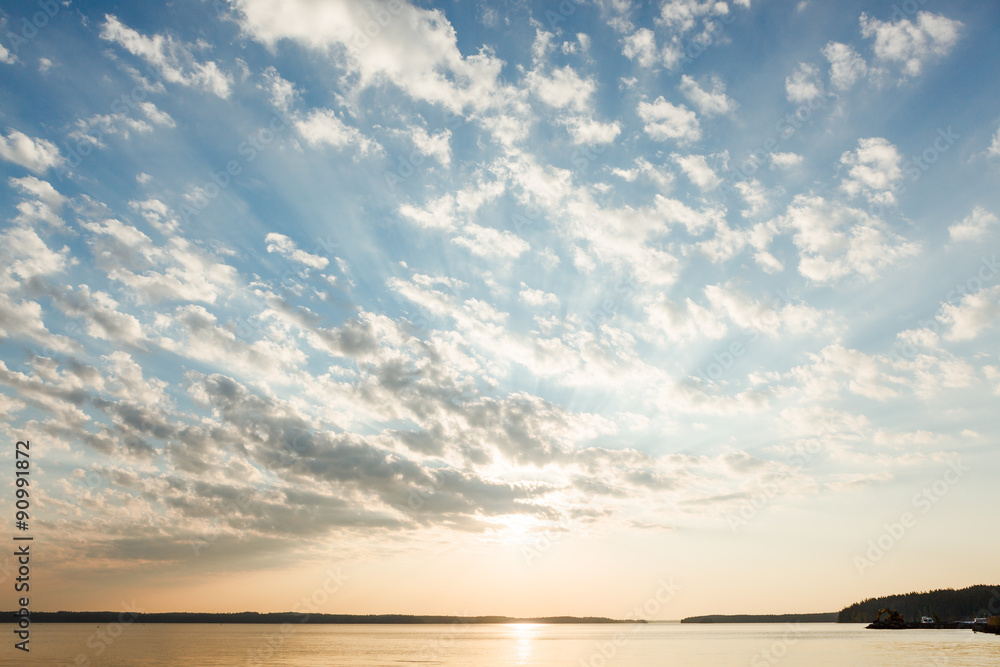 Naklejka premium Clouds and sun rays over lake at sunrise