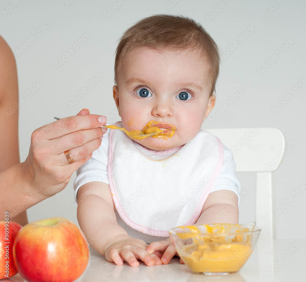 Mother feeding baby with a spoon. Spoon-feed.
