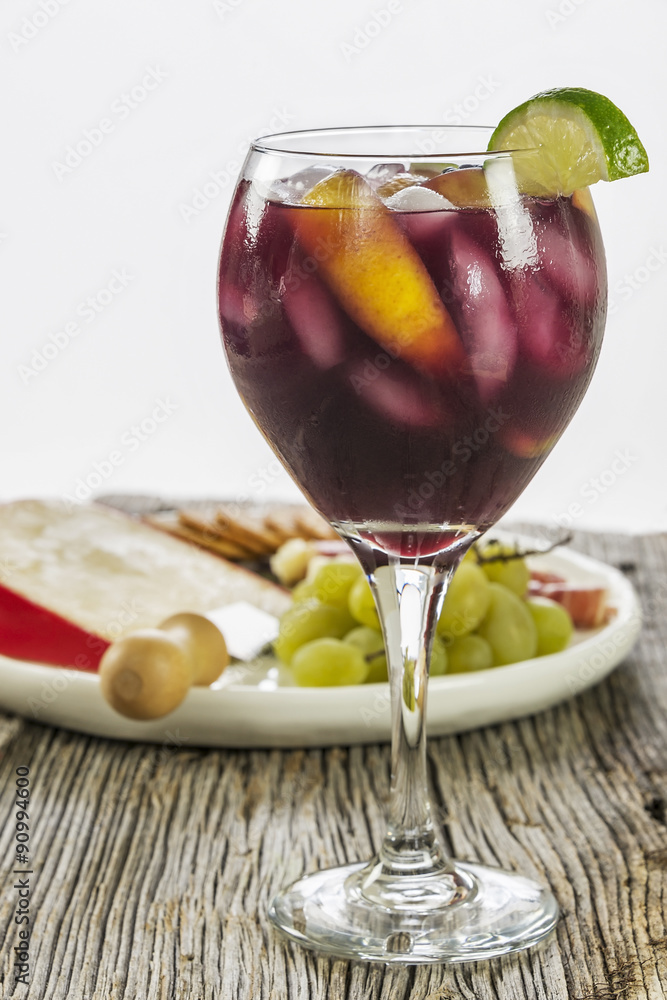 Large wine glass full of refreshing fruit filled red sangria.  The background is a rustic piece of old weathered wood combined with a white background.  