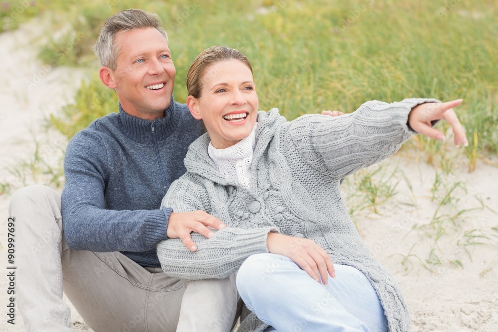 Fototapeta premium Smiling couple sitting on the sand
