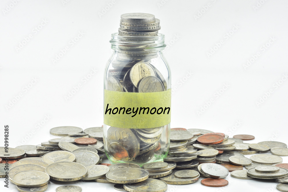 Isolated coins in jar with honeymoon label - financial concept Isolated coins in jar with honeymoon label - financial concept
