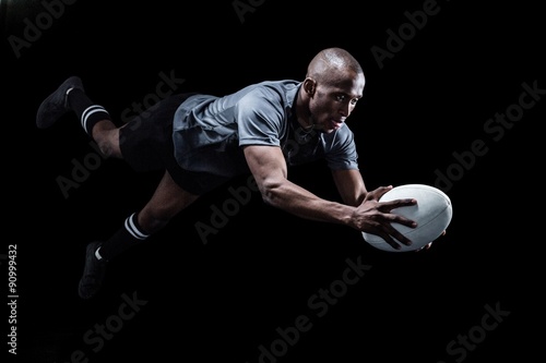 Fotografie, Obraz Sportsman jumping for catching rugby ball