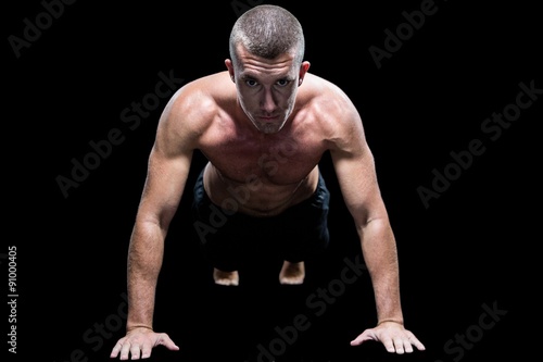 Portrait of fit shirtless athlete doing push ups