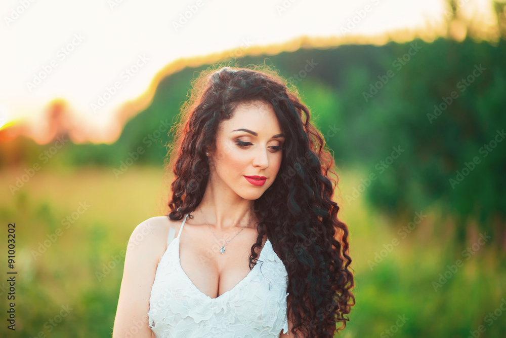 Naklejka premium beautiful young girl in a field in white dress and has long blac