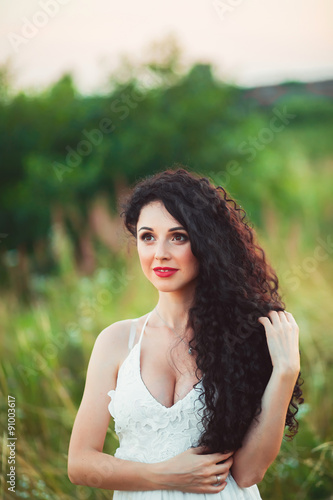 beautiful young girl in a field in white dress has beautiful lon