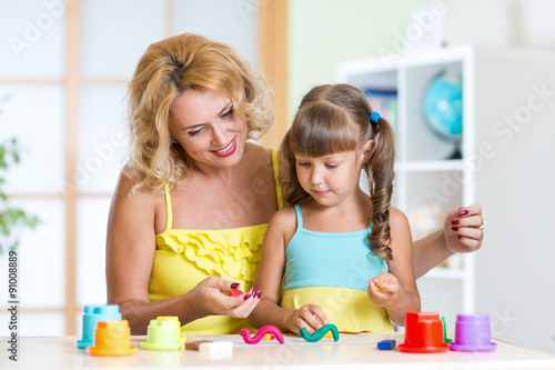 kid girl and mother playing colorful clay toy
