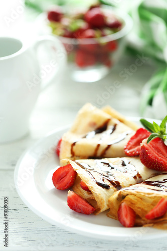 Tasty pancakes with strawberry on white wooden background