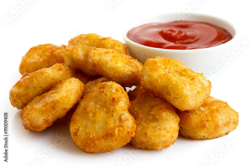 Pile of golden deep-fried battered chicken nuggets with bowl of
