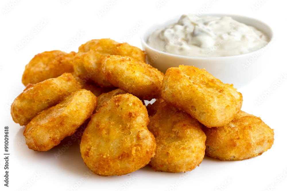 Pile of golden deep-fried battered chicken nuggets with bowl of