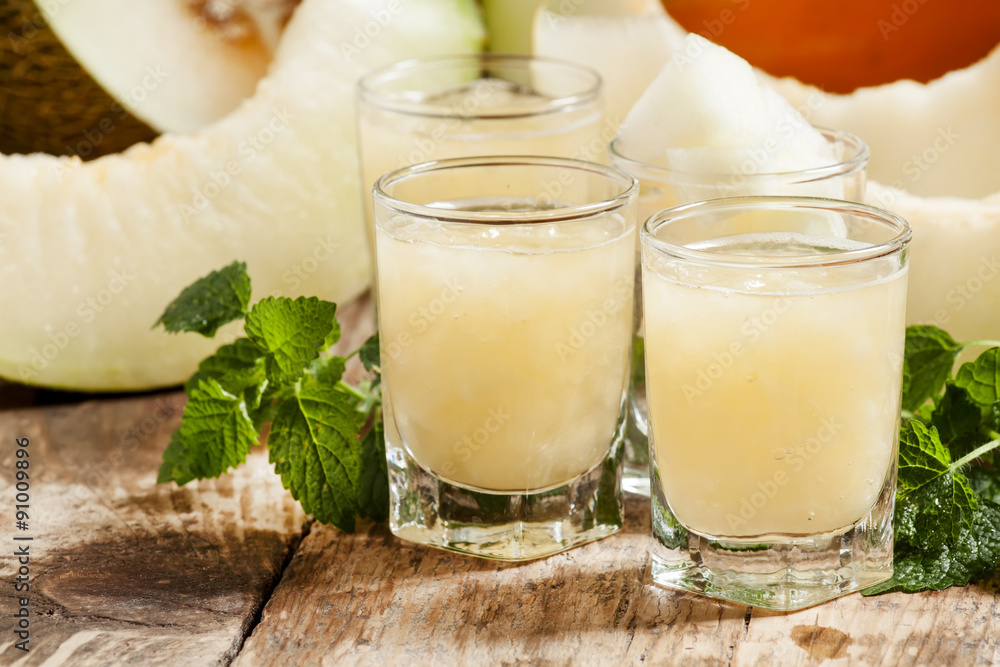 Melon juice in a glass, mint and slices of melon on a wooden ba Melon juice in a glass, mint and slices of melon on a wooden ba
