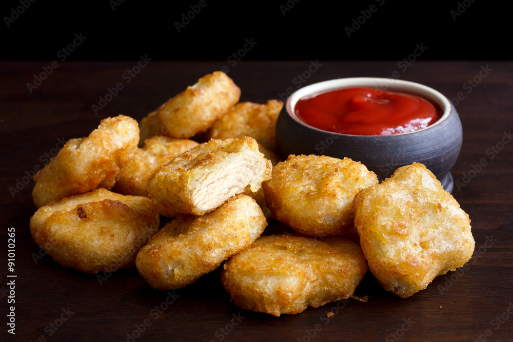 Pile of golden deep-fried battered chicken nuggets with empty ru Pile of golden deep-fried battered chicken nuggets with empty ru