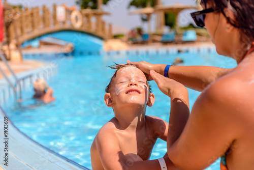 Mother putting sunscreen on her sons face