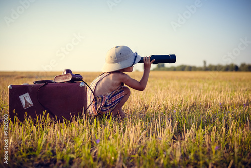 Little boy looking in spyglass on sunny field countryside photo